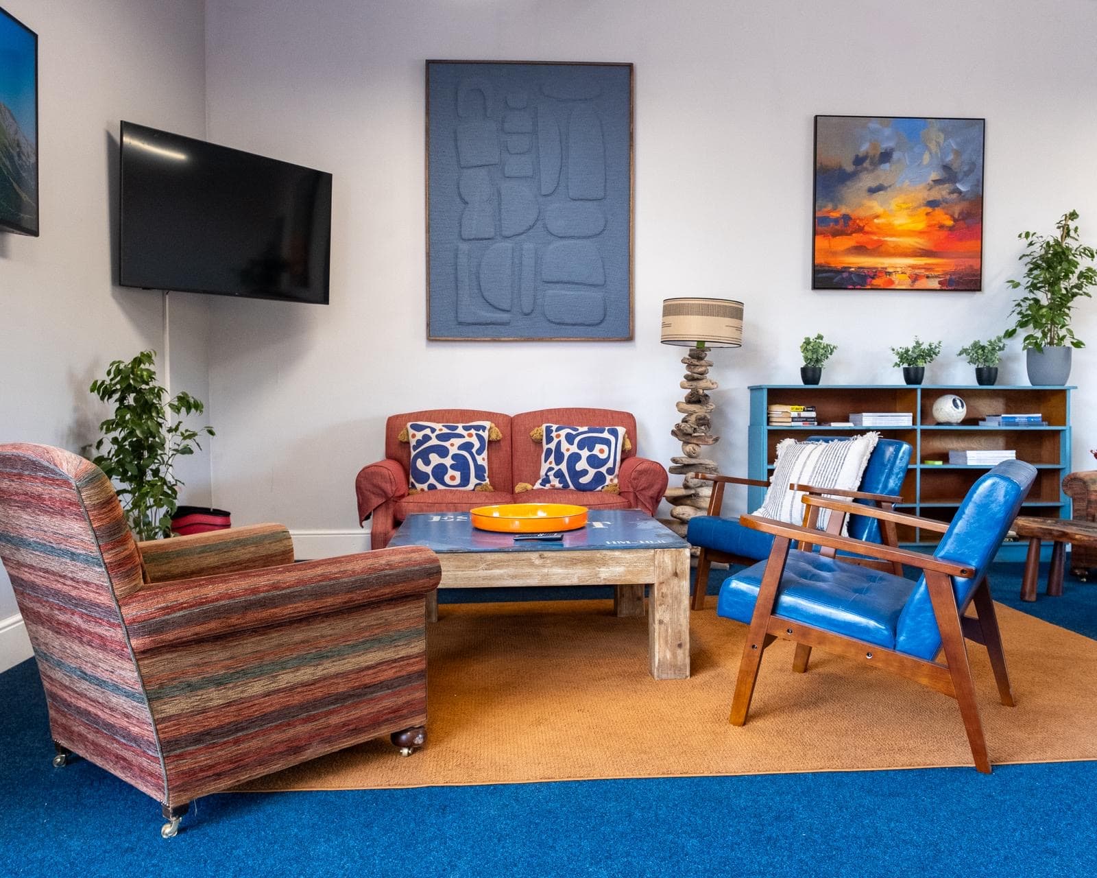 The Ashbrook Golf Zone clubhouse lounge — sofas, art on the walls and a wall-mounted TV